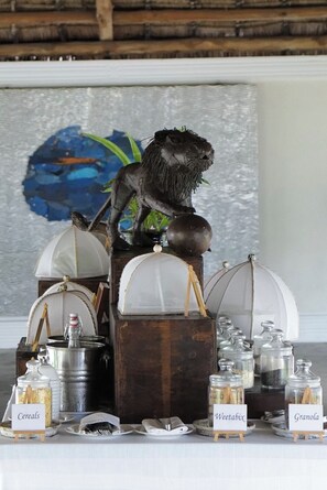 A table with food items labeled 'Cereals,' 'Weetabix,' and 'Granola,' and a decorative lion statue.