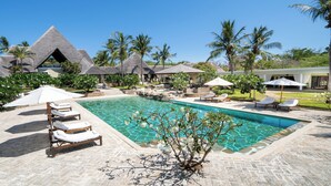 A pool area with lounge chairs, a clear pool, and thatched-roof structures. - Lion in the Sun Boutique Hotel & Spa (Malindi)
