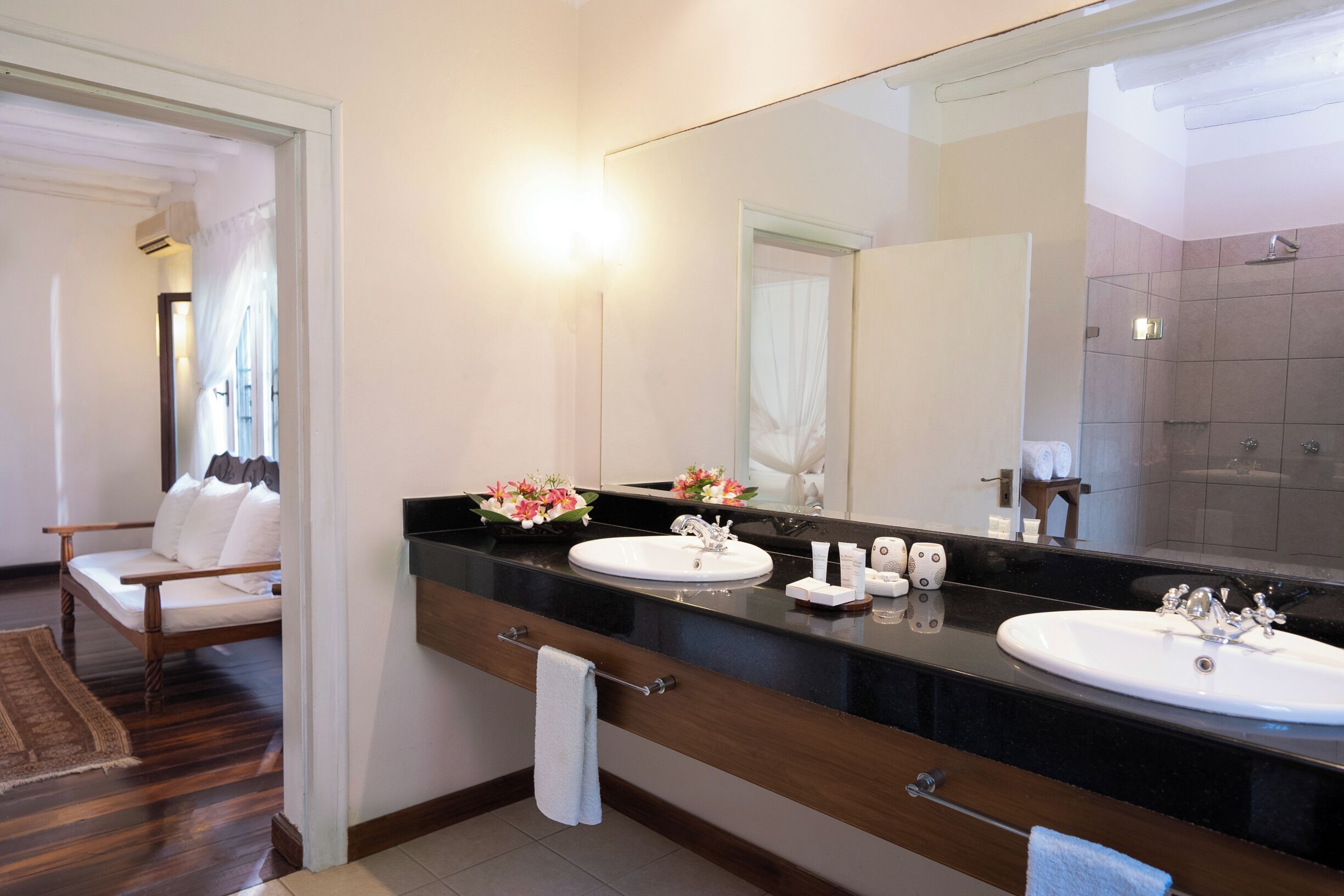 A modern bathroom with two sinks, a large mirror, and a shower area.