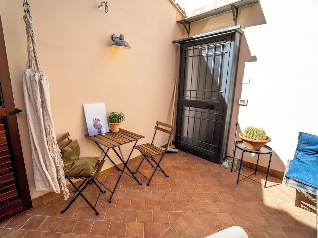 A small patio with a table and chairs, a potted plant, and a door.