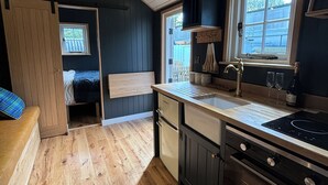 A compact kitchen with wooden flooring, a built-in oven, and a window with a view. - Rutland Rural Retreats - Shepherds Rest
 (Belton In Rutland)