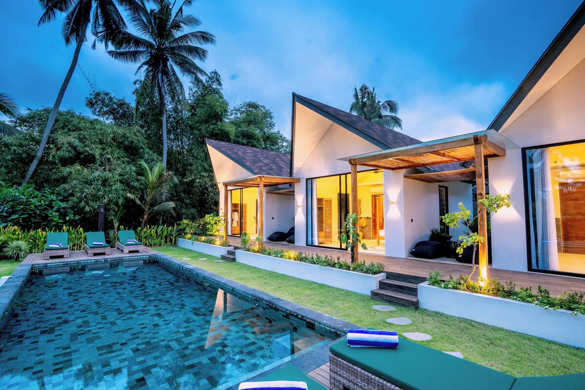 A modern house with a swimming pool, outdoor seating, and lush greenery.