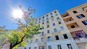 A multi-story building with balconies, large windows, and a tree in the foreground. - 4bnb - Corridoni Apartment (Rome)