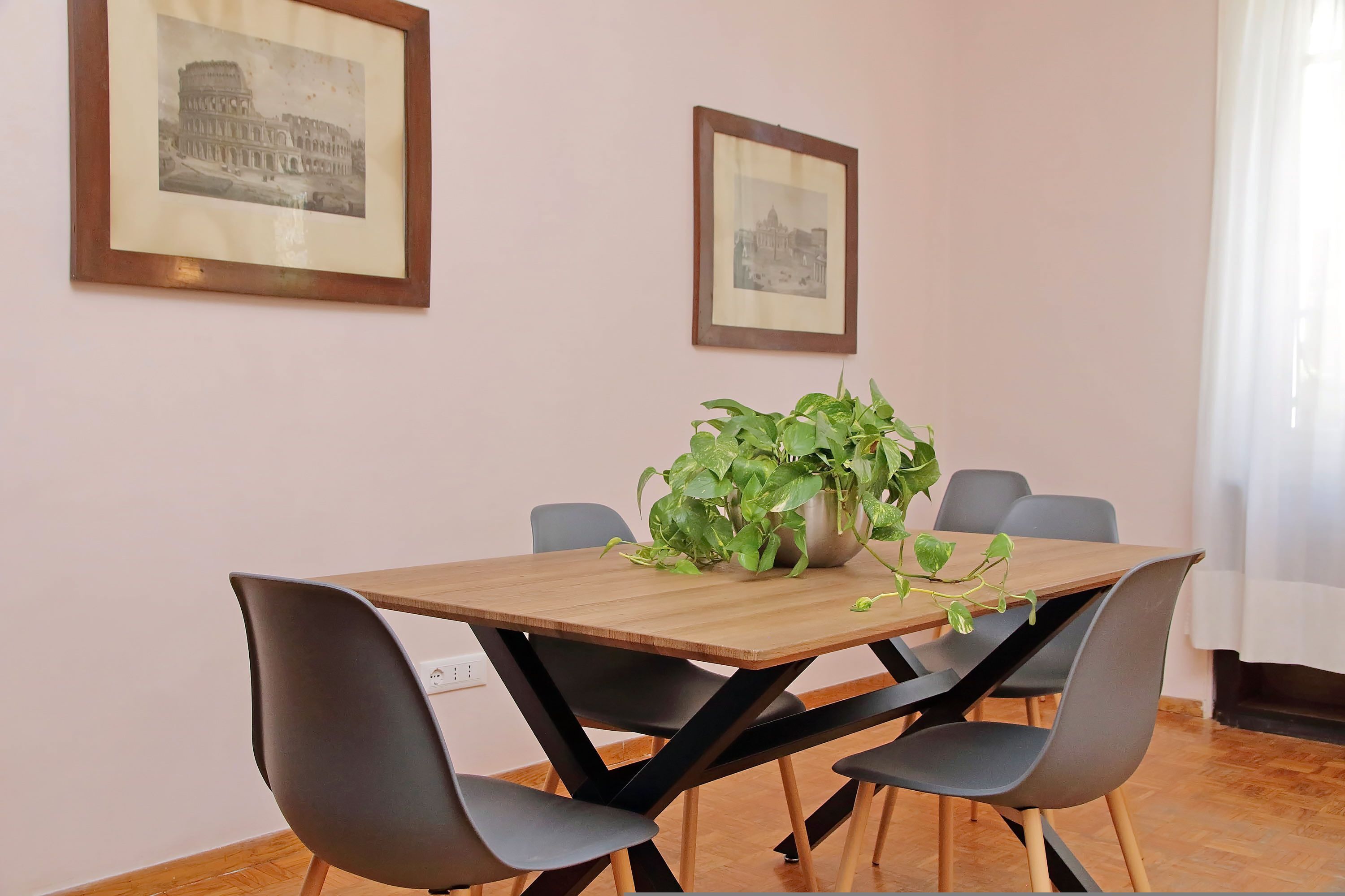 Un coin repas avec une table en bois, des chaises noires et une plante en pot.
