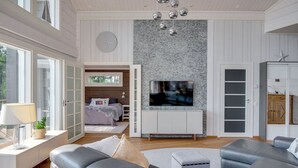 A spacious living room with a large TV, grey sofas, and a stone fireplace. - Luxury villa by the sea, Kustavi (Varsinais-Suomi)