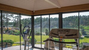 A gym with exercise equipment and large windows overlooking a green landscape. - Luxury villa by the sea, Kustavi (Varsinais-Suomi)