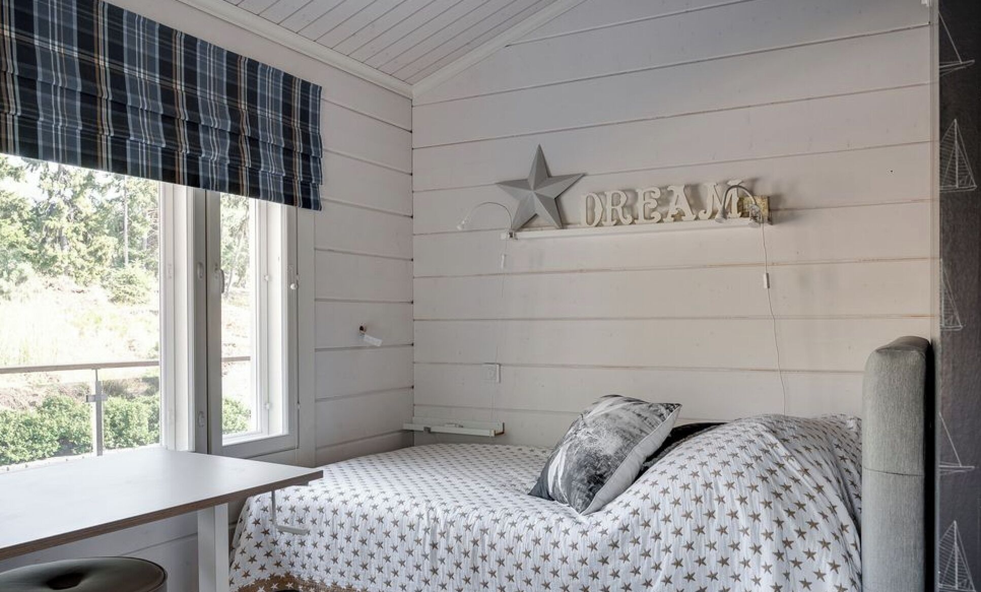 Een slaapkamer met een bed, een bureau en een raam.
