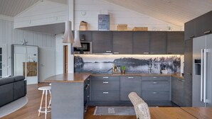 A modern kitchen with grey cabinets, a central island, and a large window with a scenic view. - Luxury villa by the sea, Kustavi (Varsinais-Suomi)