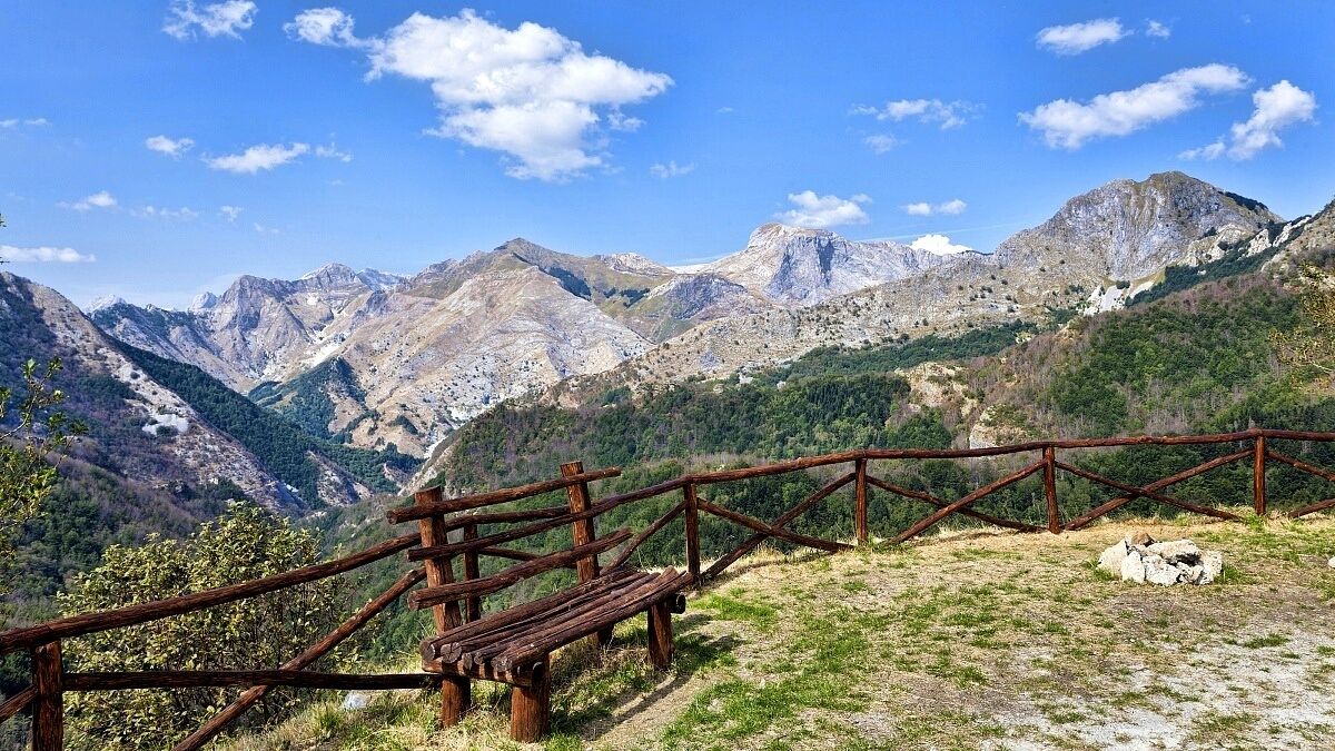 Une clôture en bois avec un banc donnant sur un paysage montagneux.