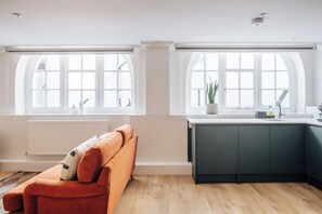A modern kitchen with a large window, a built-in oven, and a dark-colored cabinet. - The Regency by Nestor (London)