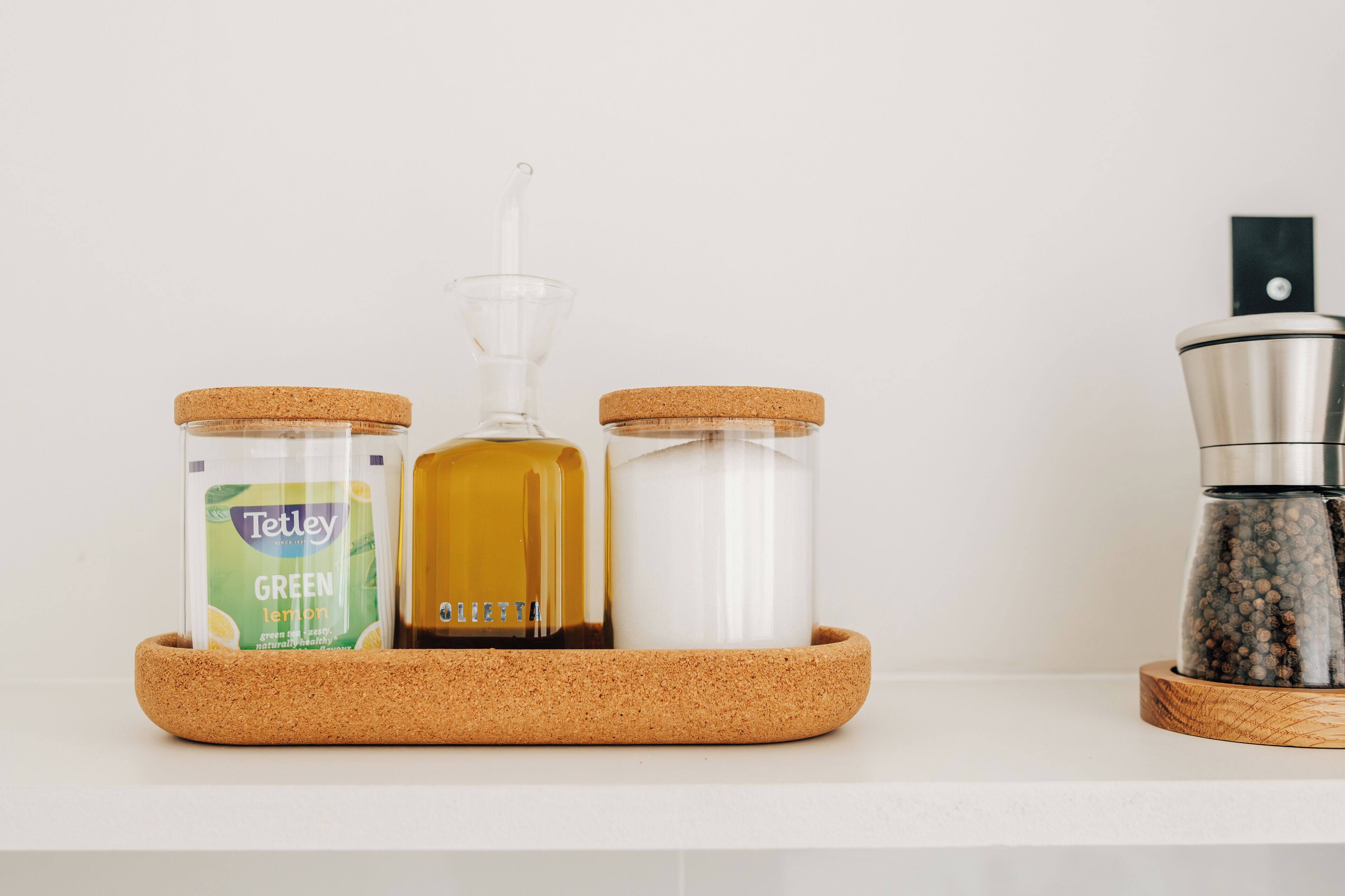Un plan de travail de cuisine avec trois récipients : une bouteille de jus de citron verte, une bouteille d’huile jaune et un salier blanc.