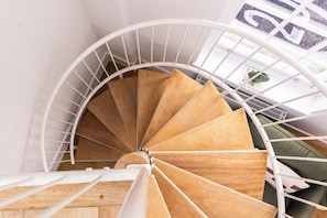 A spiral staircase with wooden steps and white railings, leading to an upper floor. - The Regency by Nestor (London)