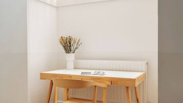 A small, bright room with a wooden desk and chair, a radiator, and a window with a grid pattern.