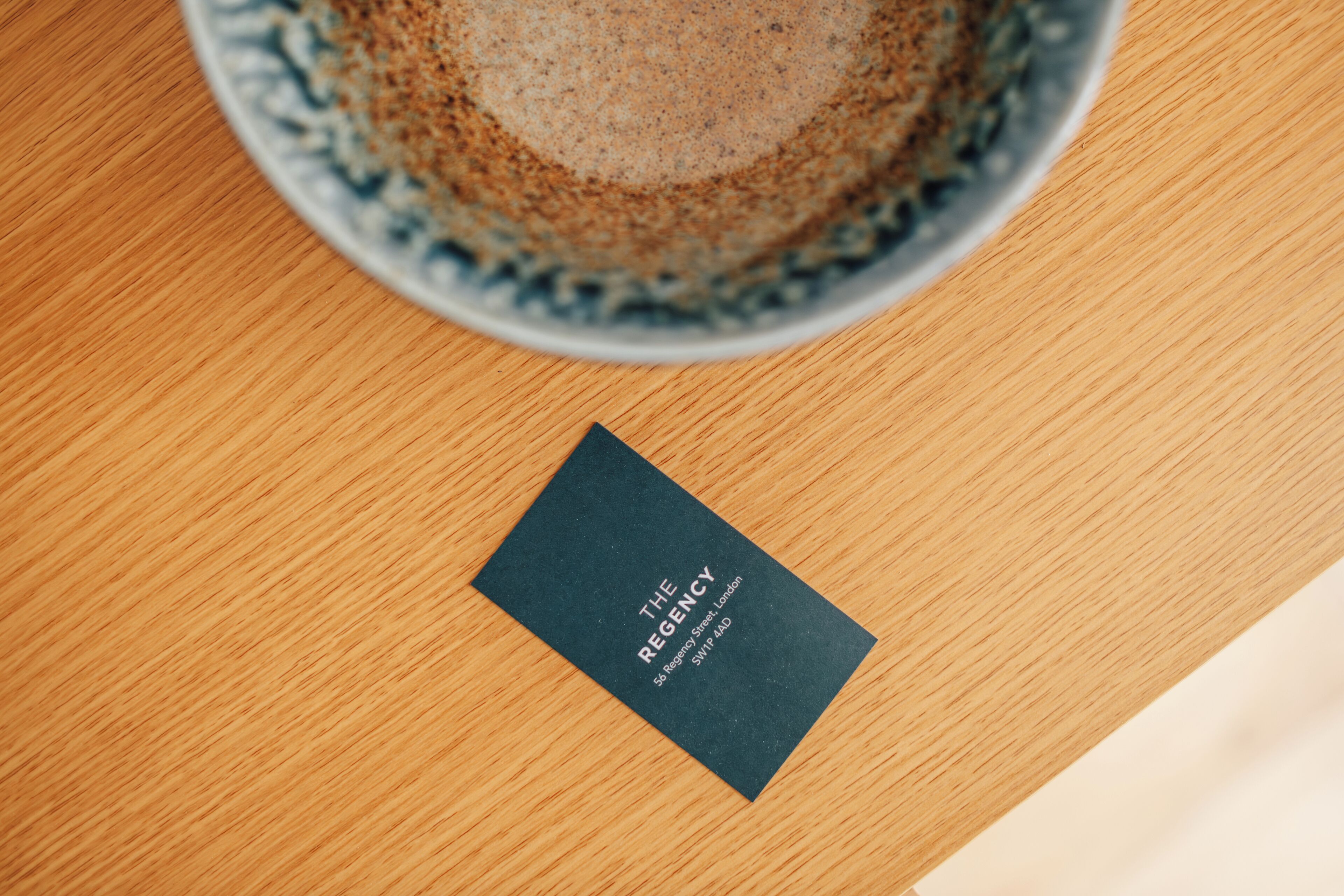 A business card on a wooden surface with a coffee cup in the background.