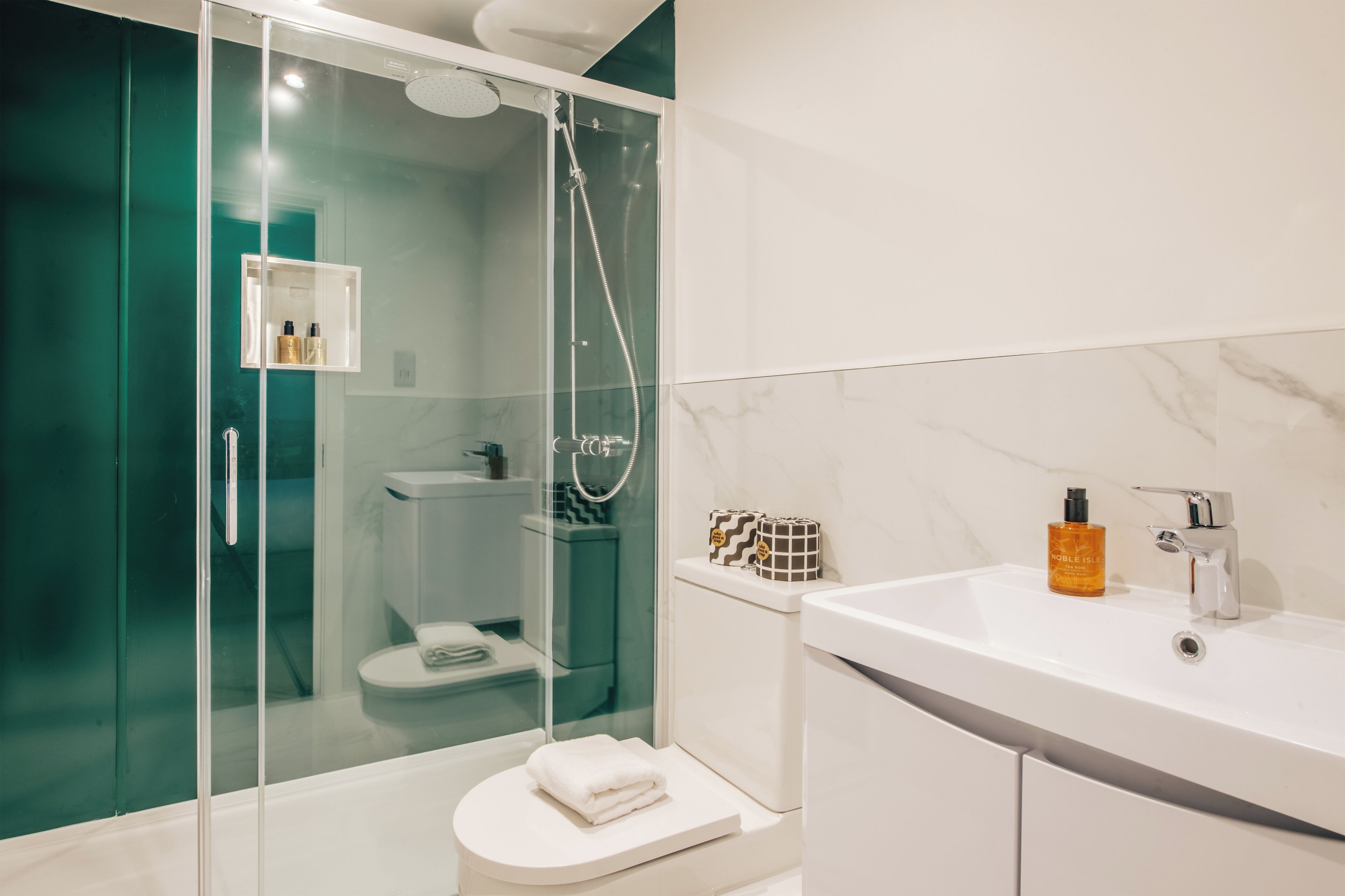 A modern bathroom with a glass-enclosed shower, a white sink, and a marble backsplash.