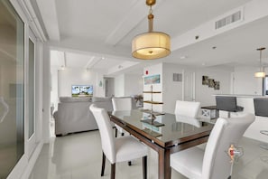 Un comedor moderno con una mesa de vidrio, sillas blancas y una lámpara colgante.