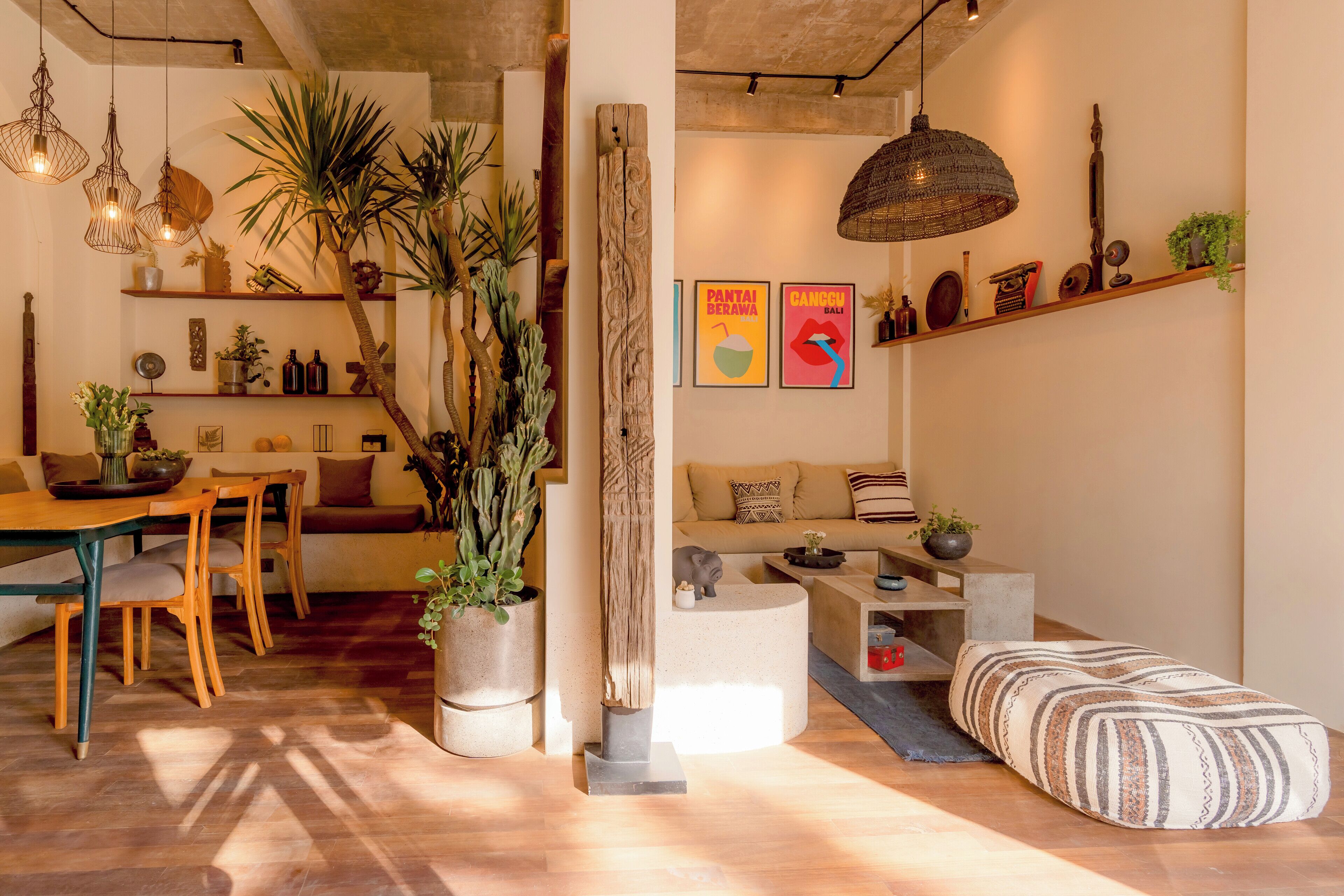 Un salon chaleureux avec une table à manger en bois, des sièges confortables et divers objets décoratifs, notamment des plantes et des œuvres d’art.