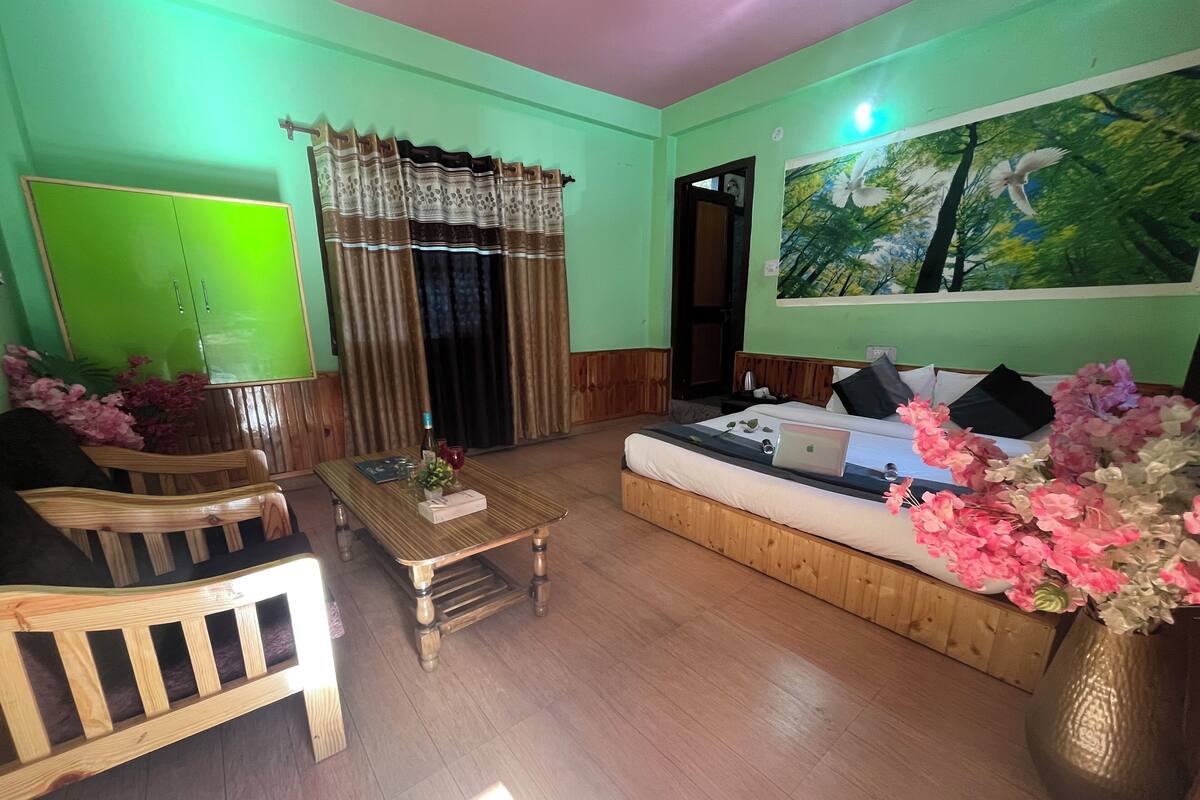 A room with a green wall, a wooden sofa, a wooden coffee table, and a large painting of birds.