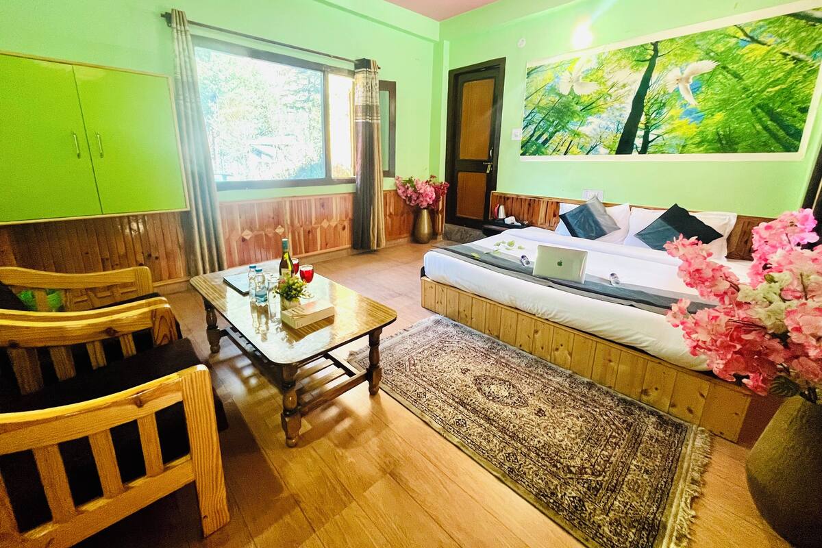 A room with a bed, a wooden table, a chair, a window, and a painting on the wall.