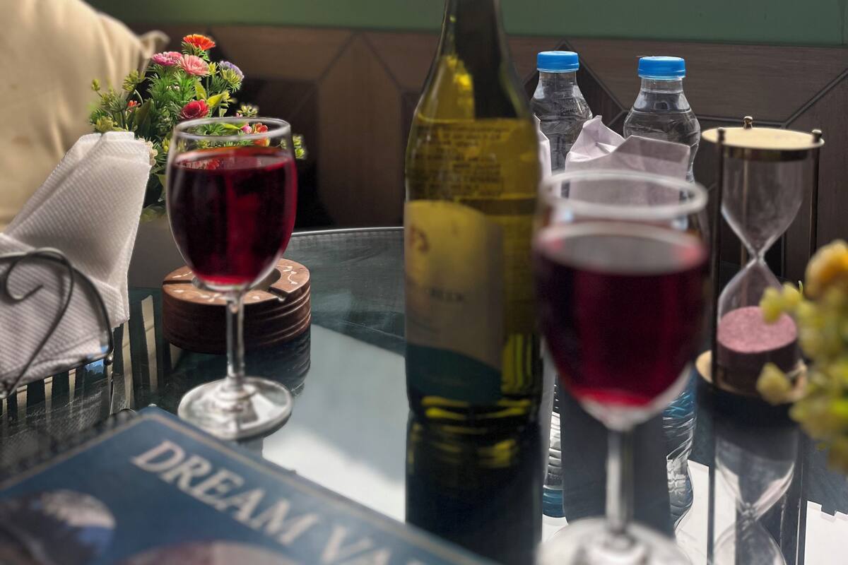 A table with a bottle of wine, glasses of red wine, and a water bottle.