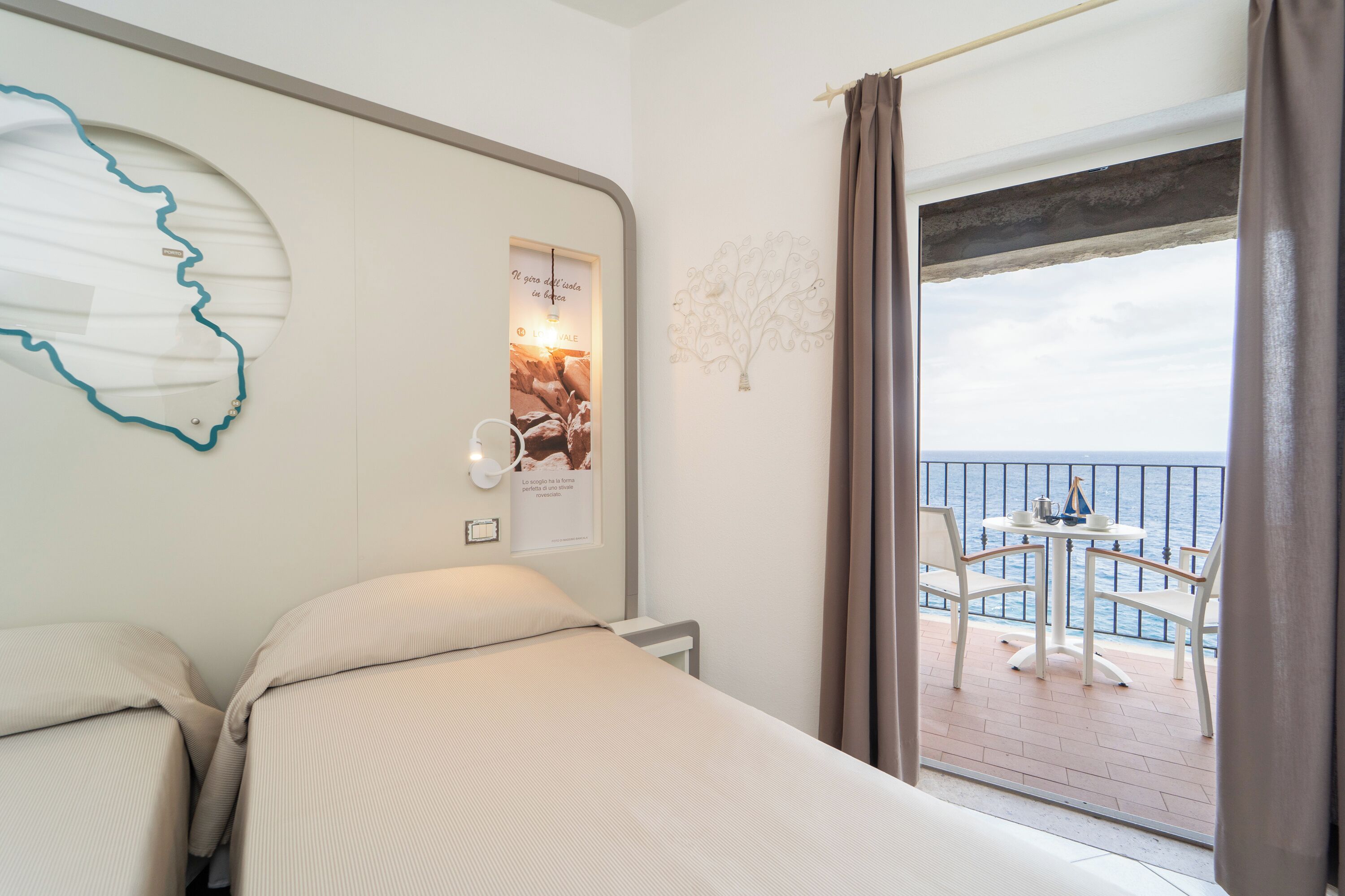 Een hotelkamer met een bed, wanddecoratie en een balkon met een tafel en stoelen.