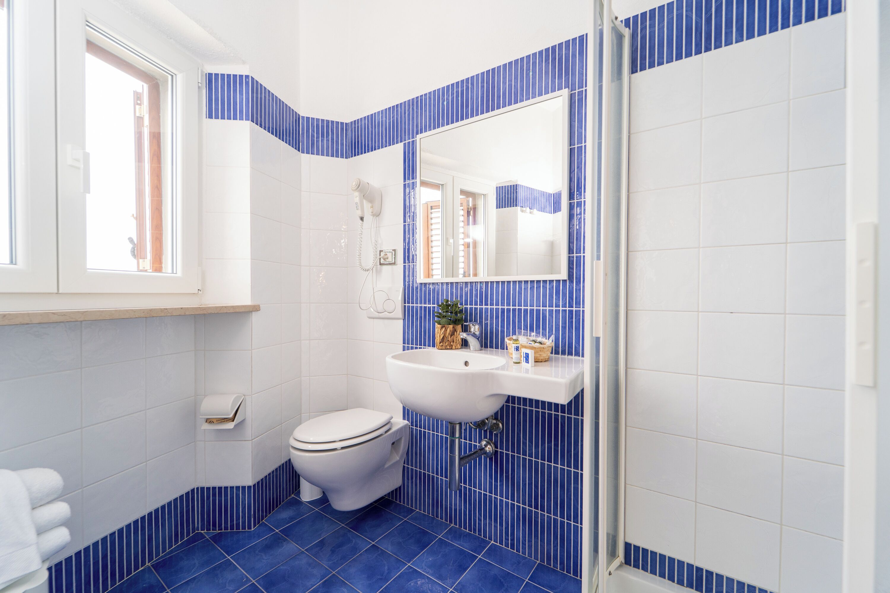 Un baño con inodoro blanco, lavamanos y espejo.