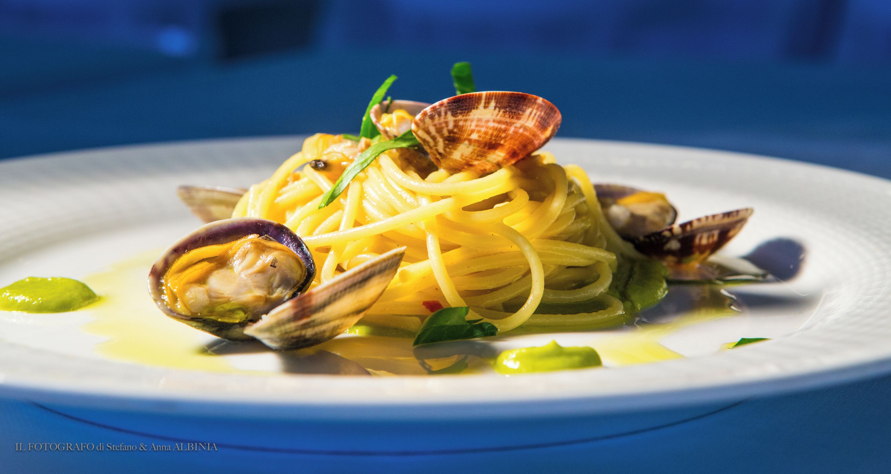 A plate of pasta with clams and green garnish.