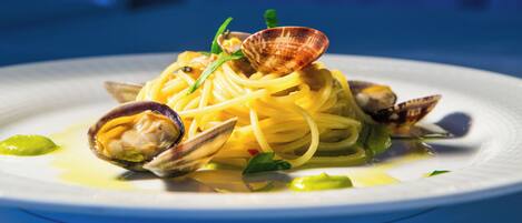 A plate of pasta with clams and green garnish.