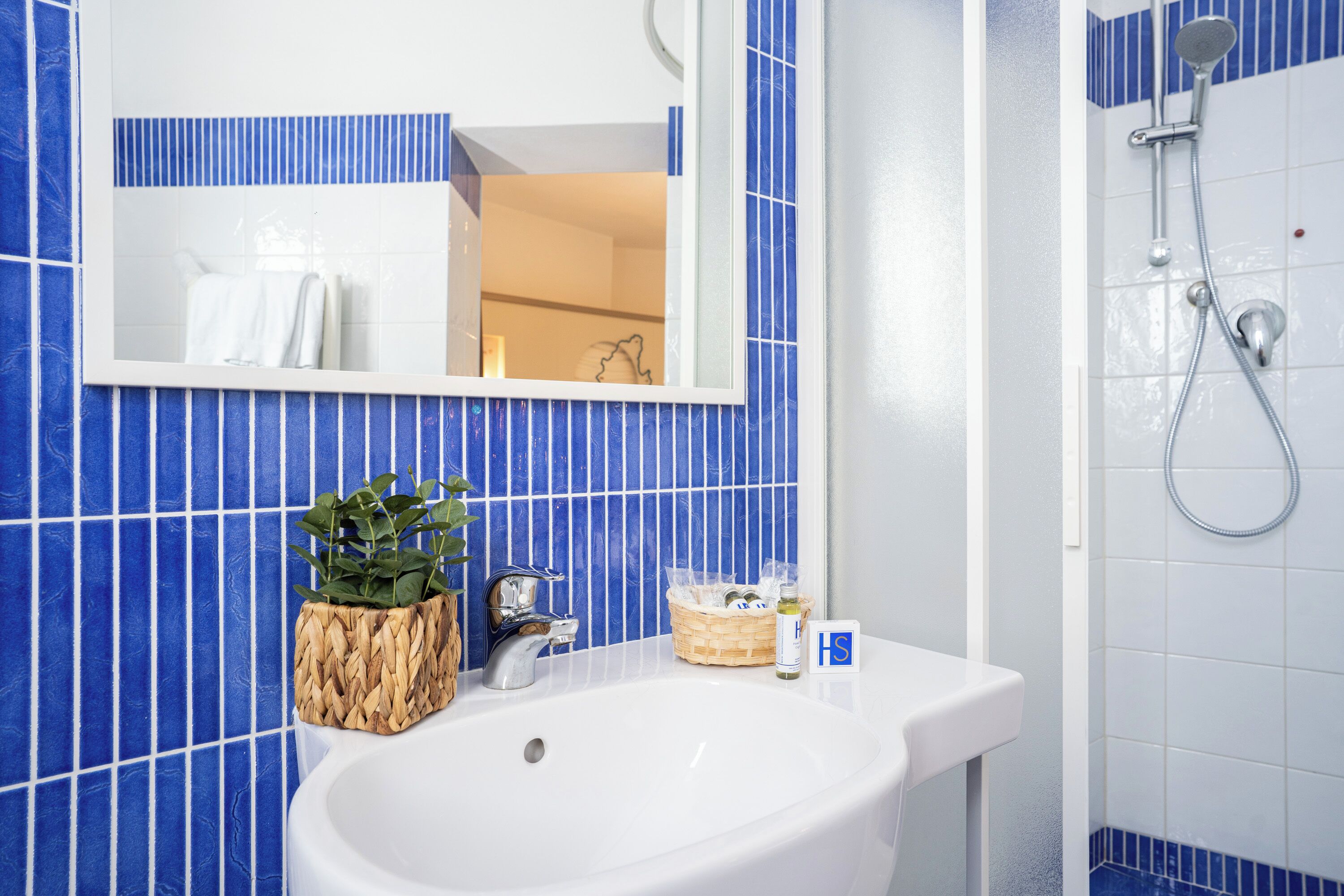 Ein Badezimmer mit einem weißen Waschbecken, einem Spiegel und einer Dusche.