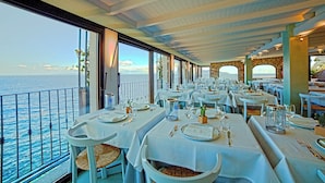 A restaurant with tables set for dining, overlooking the sea. - Hotel Saraceno (Isola del Giglio)