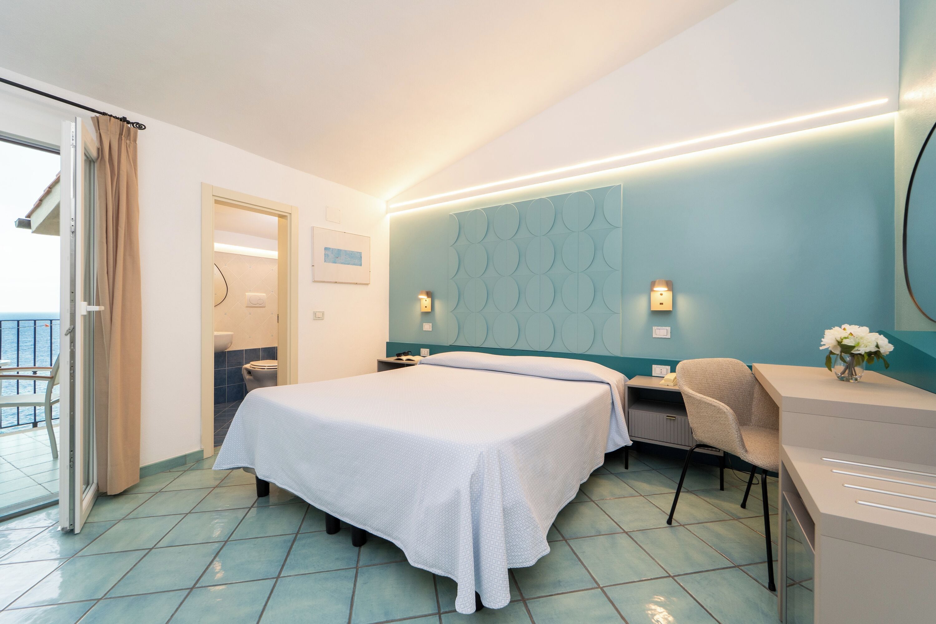 Una habitación de hotel con cama, escritorio, silla y vistas al exterior.