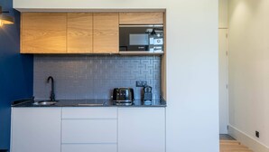 Eine moderne Küche mit Holzschränken, einer schwarzen Arbeitsplatte und einer Bosch-Kaffeemaschine.