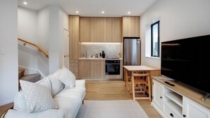 Une cuisine moderne avec des meubles en bois, un four encastré et un réfrigérateur en acier inoxydable.