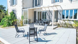An outdoor patio with a table and chairs, a covered seating area, and a building with large windows and shutters. - Le Domaine du Pavillon • The idyllic Brenne (Nuret-le-Ferron)
