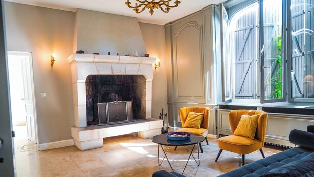 A living room with a fireplace, two armchairs, a sofa, and a large window with a view of greenery. - Le Domaine du Pavillon • The idyllic Brenne (Nuret-le-Ferron)