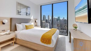 Moderni hotellihuone, jossa on suuri sänky, työpöytä ja näkymä kaupunkiin.