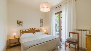 A bedroom with a bed, bedside tables, a chair, a radiator, and a view of the outside. - Casa Melograno by Interhome (Sestri Levante)