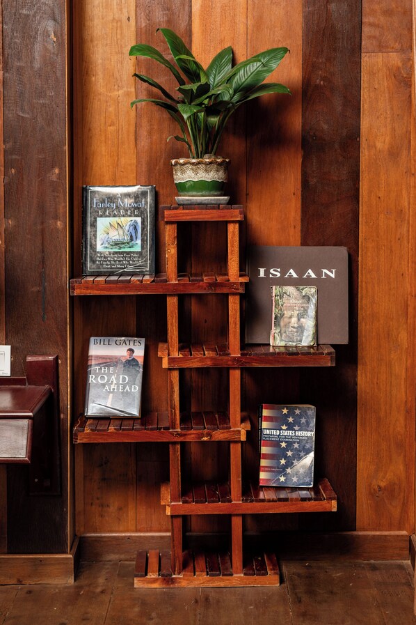 Una estantería de madera con libros y una planta en maceta.
