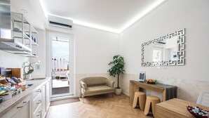 A modern kitchen with a herringbone floor, a built-in oven, and a dining area with a wooden table and stools. - Colonna Inn (Rome)