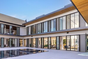 A modern multi-story house with large glass windows, a swimming pool, and an open-plan living area. - Villa Amarasara (Pa Klok)