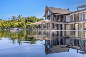 A modern house with a pool, lounge chairs, and umbrellas. - Villa Amarasara (Pa Klok)