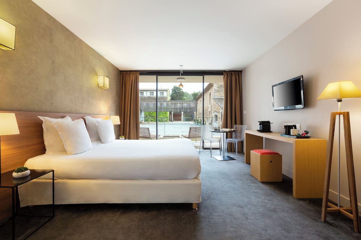 Habitación de hotel con una cama grande, un escritorio, televisión y vistas al exterior.