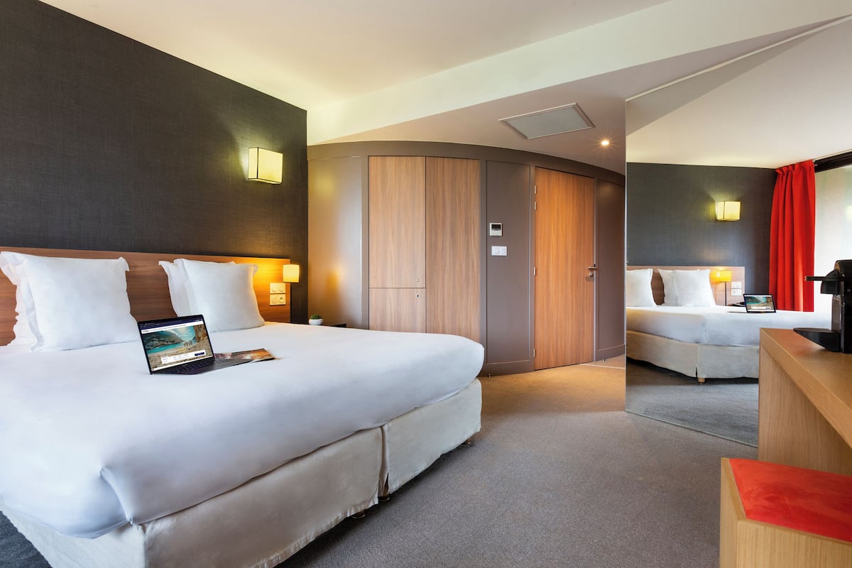 Una habitación de hotel con una cama grande, un escritorio y un armario.