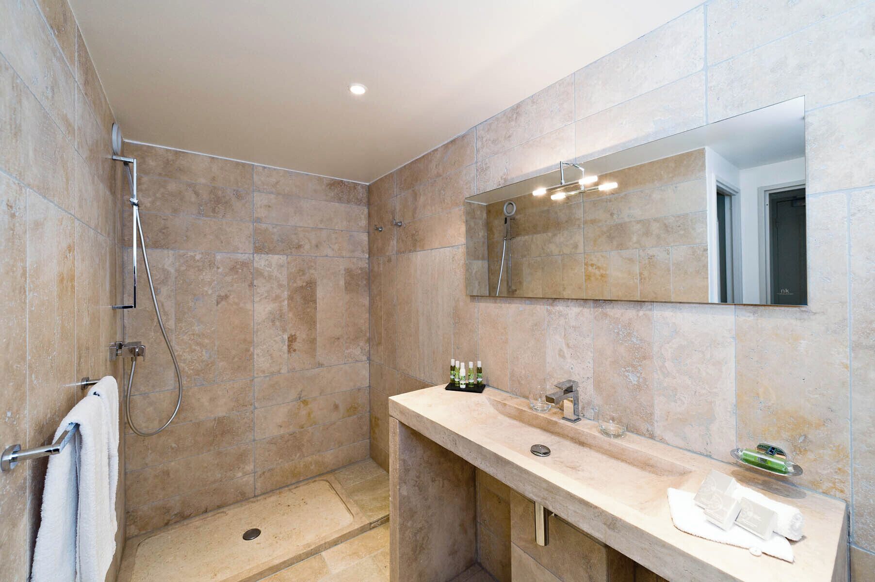 Une salle de bain moderne avec une douche à l’italienne, un meuble-lavabo et un grand miroir.