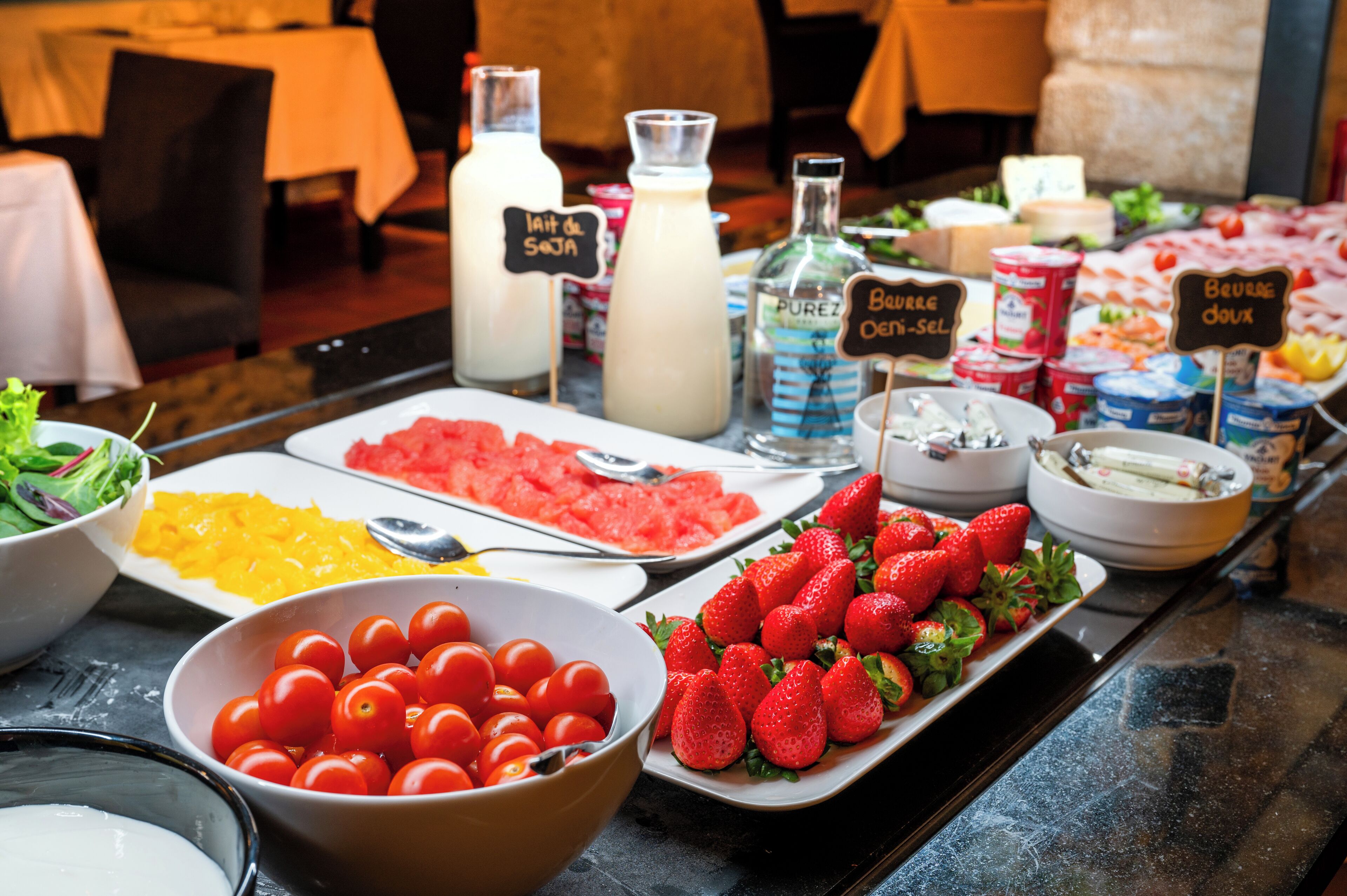 A buffet table with various food items including tomatoes, strawberries, and different types of cheese.