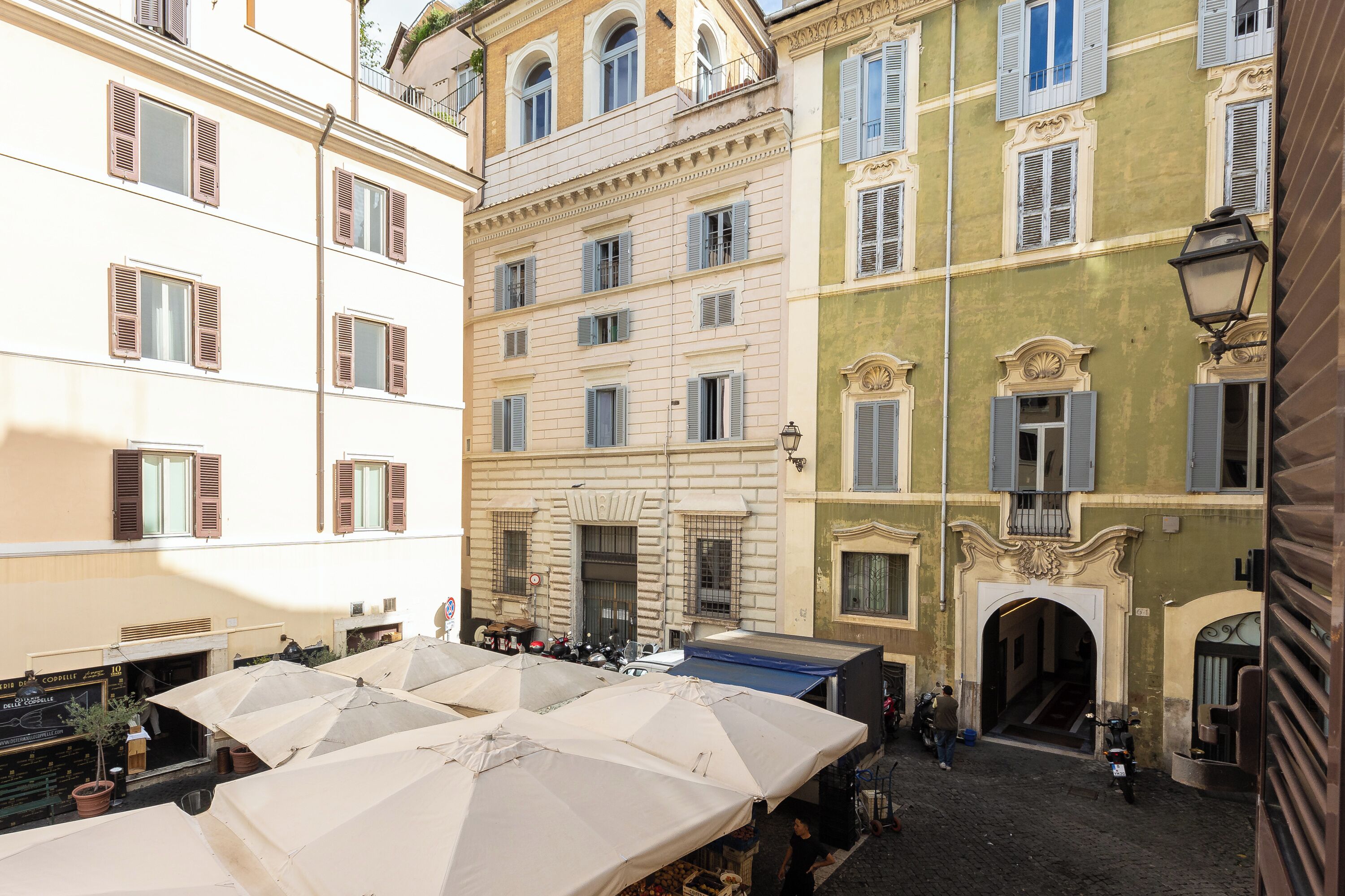 A courtyard with multiple buildings, outdoor seating, and a cobblestone street.