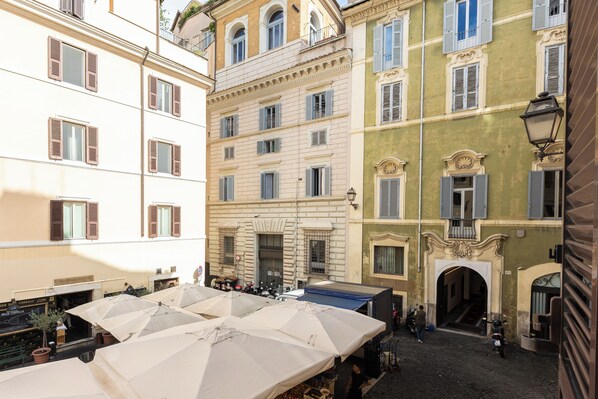 A courtyard with multiple buildings, outdoor seating, and a cobblestone street.