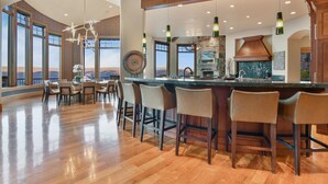 A spacious kitchen with a large island, bar stools, and a view of the mountains.