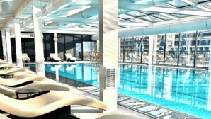 A modern indoor pool area with lounge chairs and a clear view of the pool.