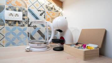 A kitchen counter with a coffee maker, a glass container, and a box of tea bags.